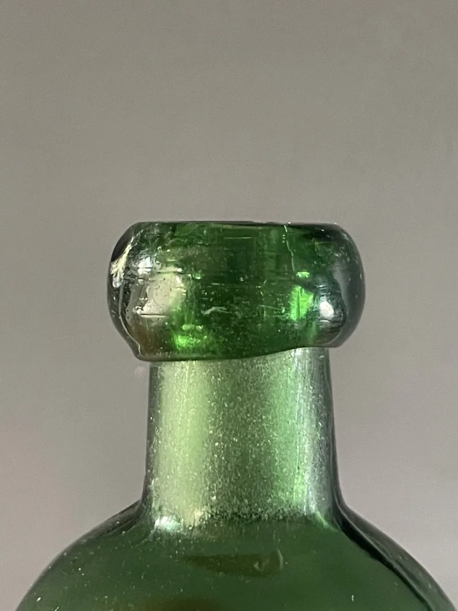 The neck and closure of the green Savage & Son bottle